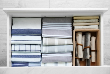 Photo of Open drawer with folded napkins and towels indoors, top view. Order in kitchen