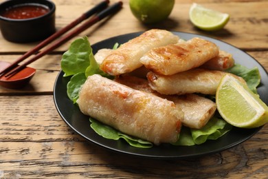 Photo of Tasty fried spring rolls served on wooden table, closeup