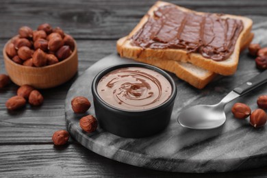 Photo of Bowl with chocolate paste, tasty toast and nuts on wooden table