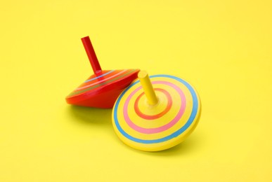 Photo of Two bright spinning top on yellow background. Toy whirligig