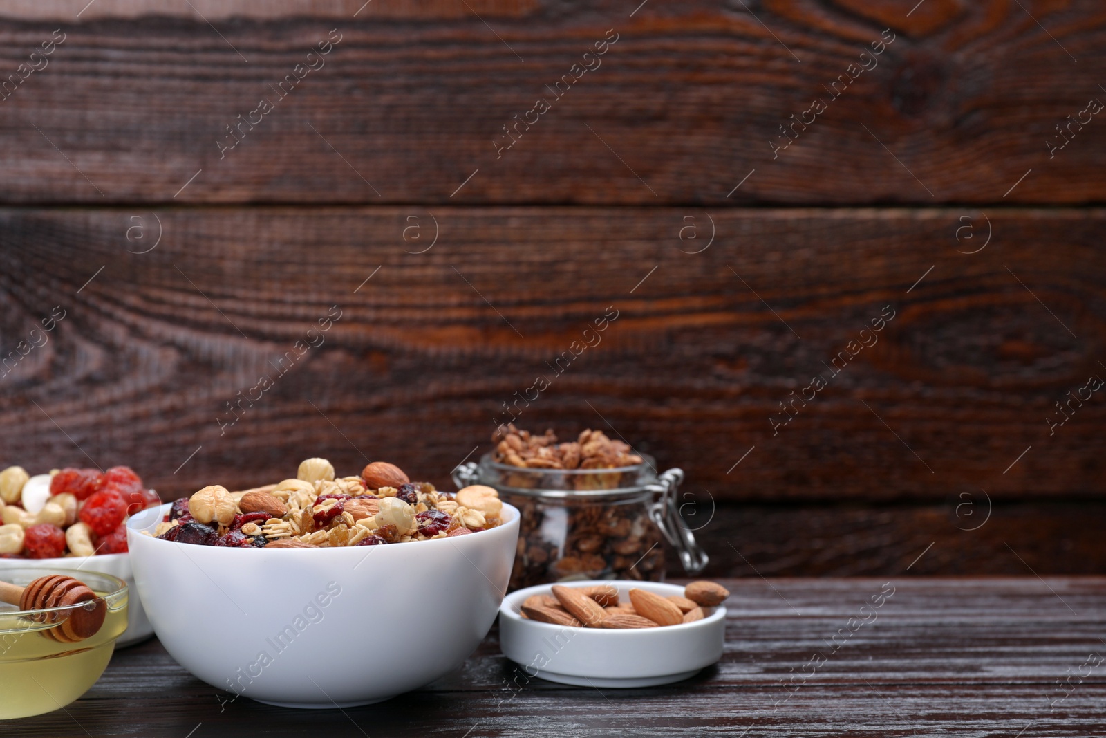Photo of Tasty granola with nuts, different ingredients on wooden table. Space for text