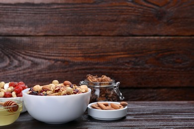 Tasty granola with nuts, different ingredients on wooden table. Space for text