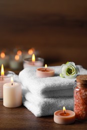 Photo of Beautiful spa composition with burning candles and flower on wooden table