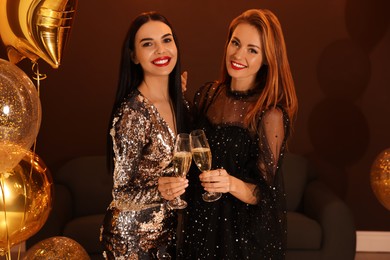 Happy women with glasses of sparkling wine celebrating New Year indoors