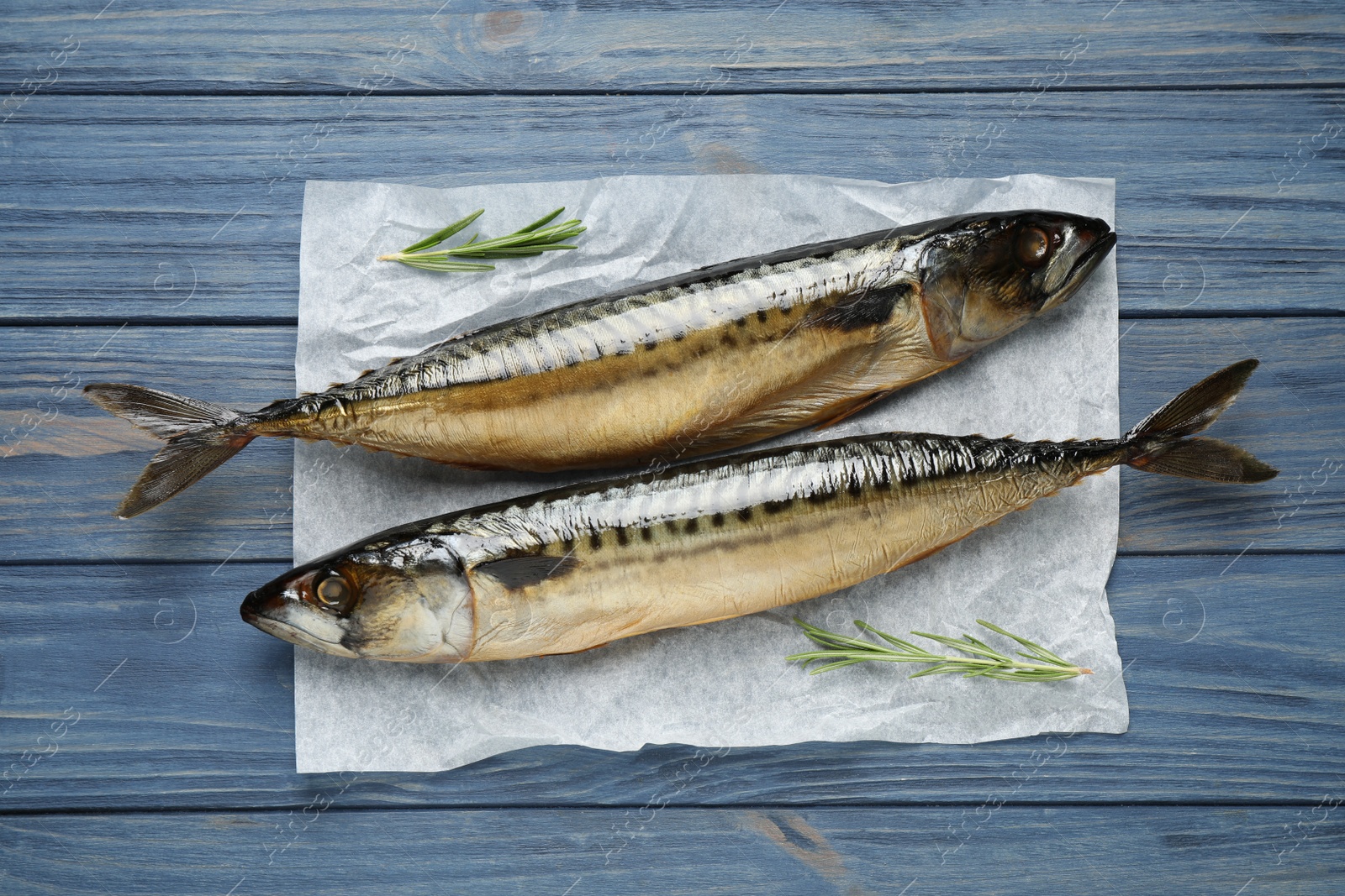 Photo of Tasty smoked fish on blue wooden table, top view