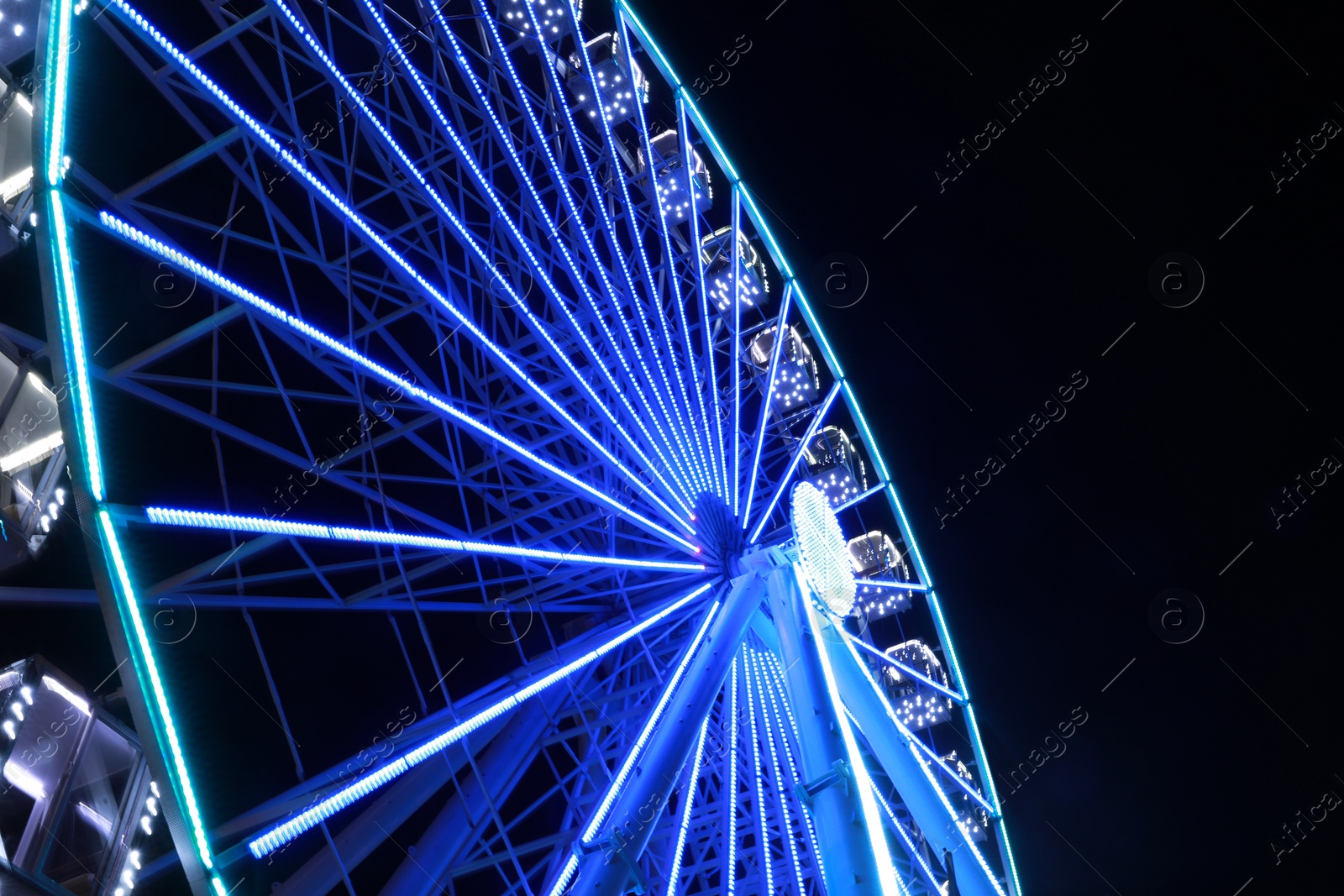 Photo of Beautiful glowing Ferris wheel against dark sky, low angle view