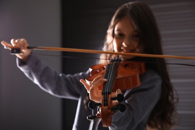 Photo of Preteen girl playing violin in studio at music lesson, focus on hand