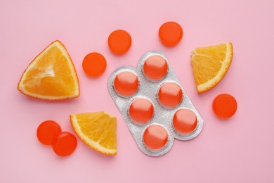 Photo of Many orange cough drops on pink background, flat lay