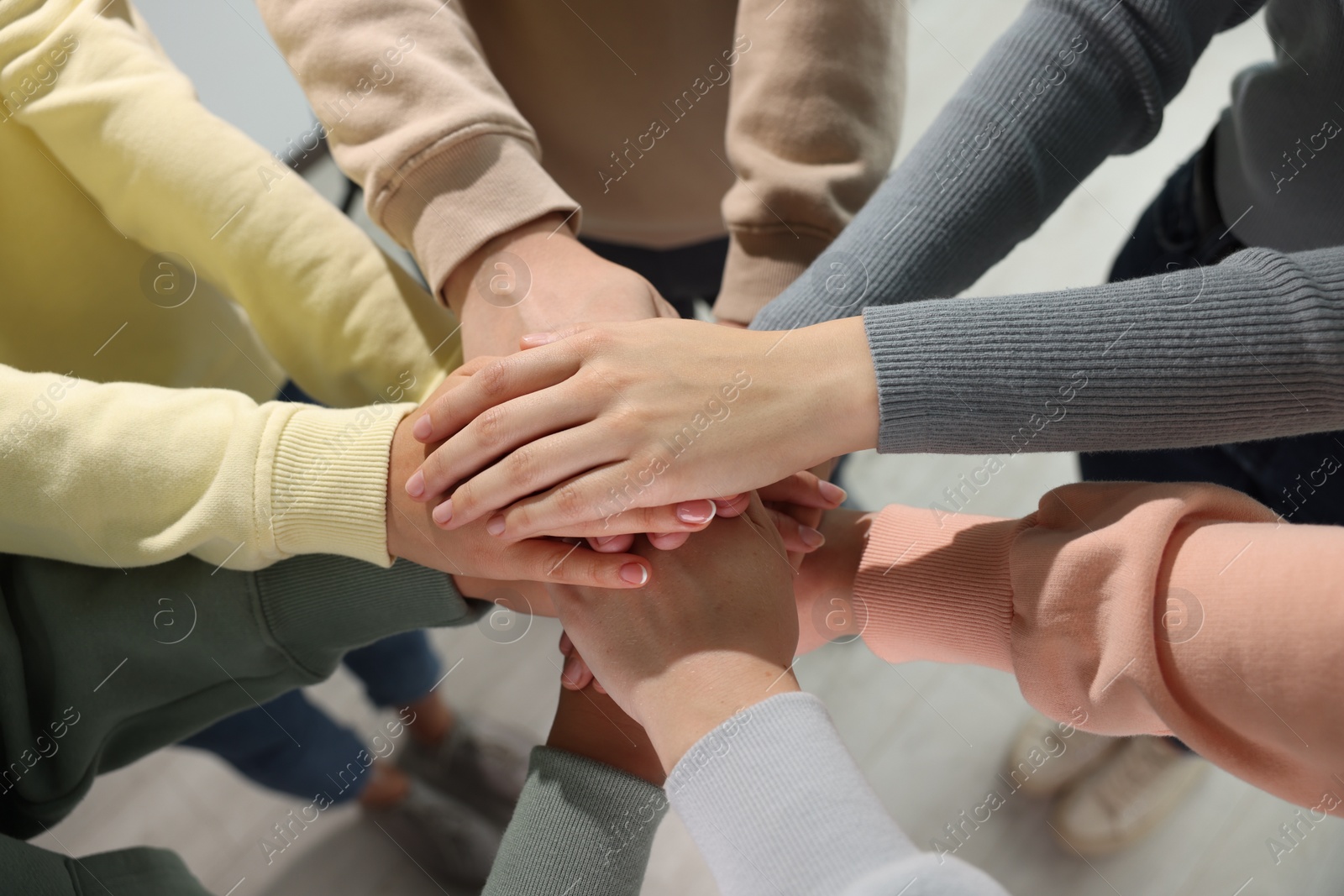 Photo of Group of people holding hands together indoors, above view. Unity concept