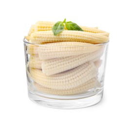 Photo of Canned baby corns with basil in glass on white background