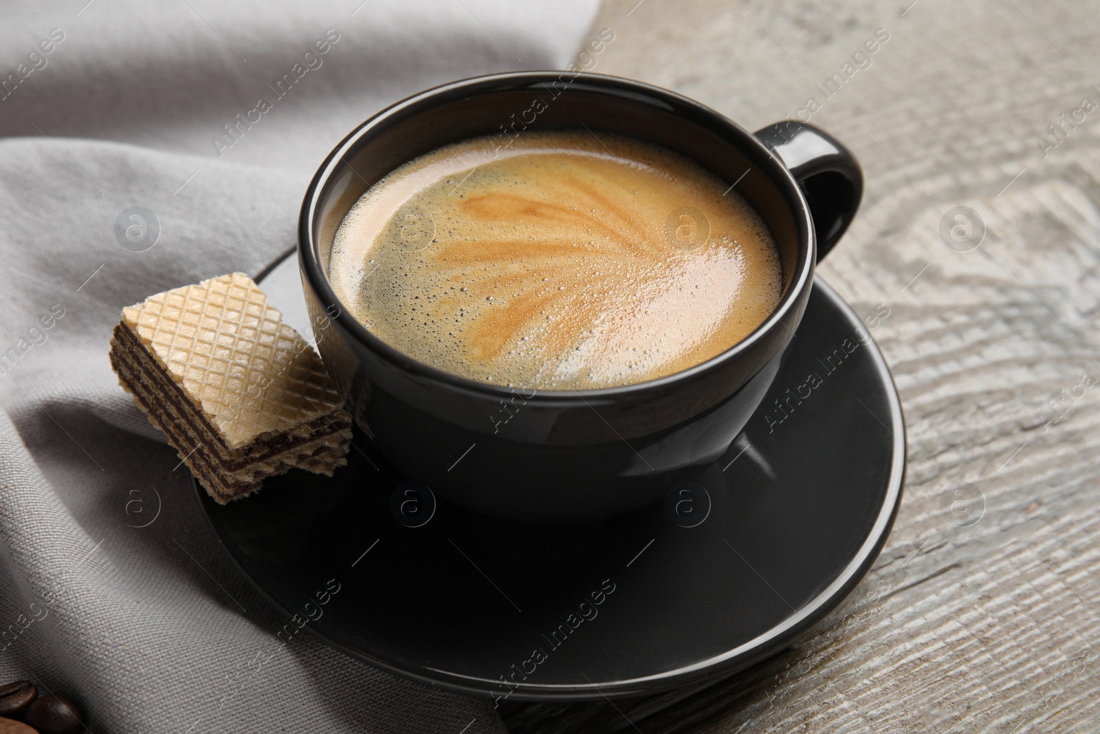 Photo of Delicious wafer and cup of coffee for breakfast on wooden table