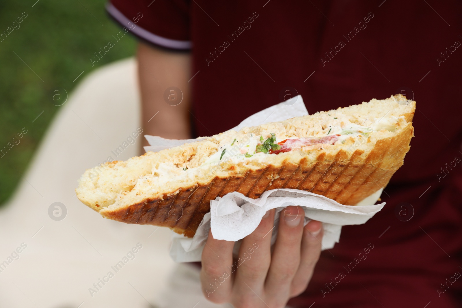 Photo of Man holding delicious sandwich outdoors, closeup. Street food