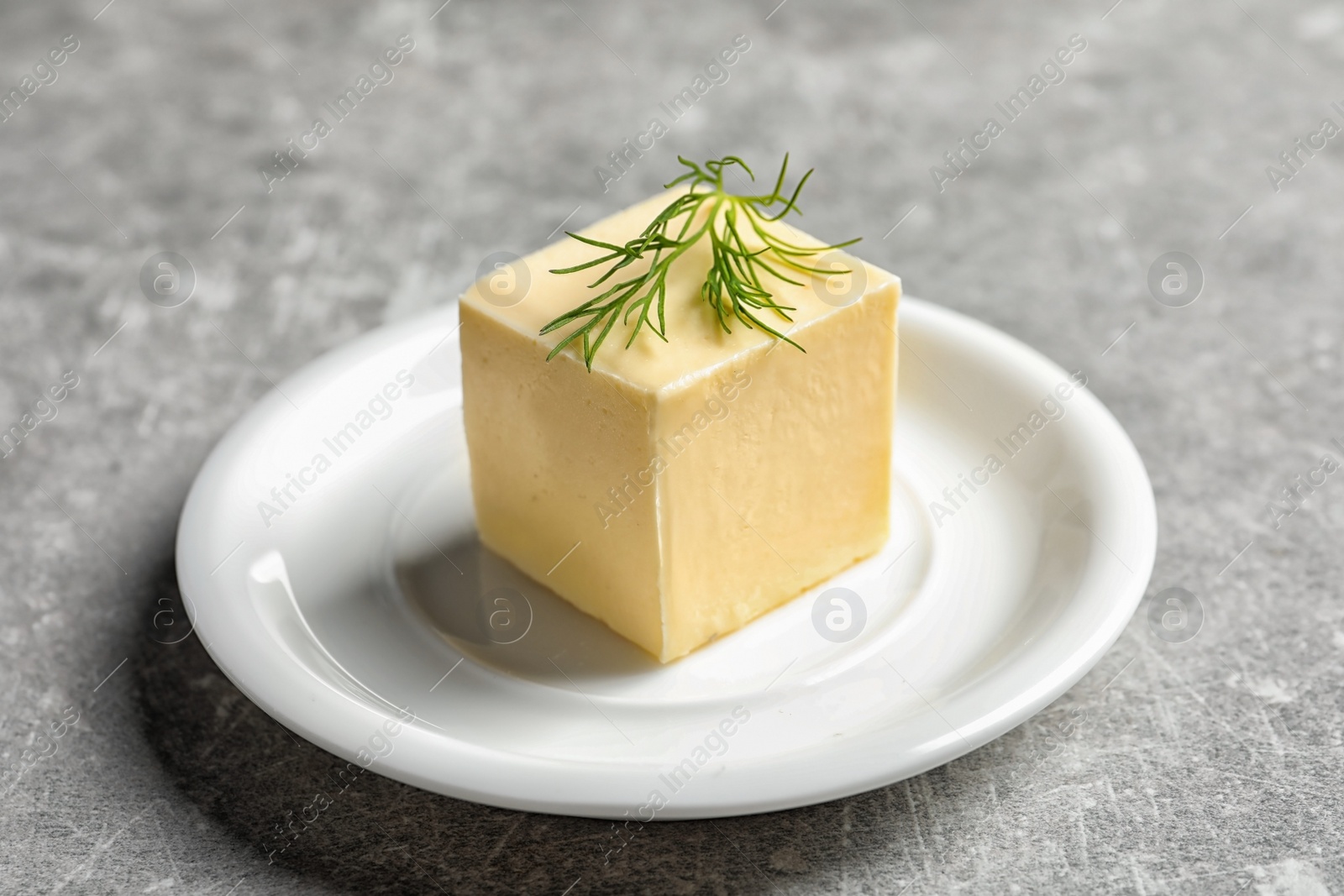 Photo of White plate with fresh butter on table