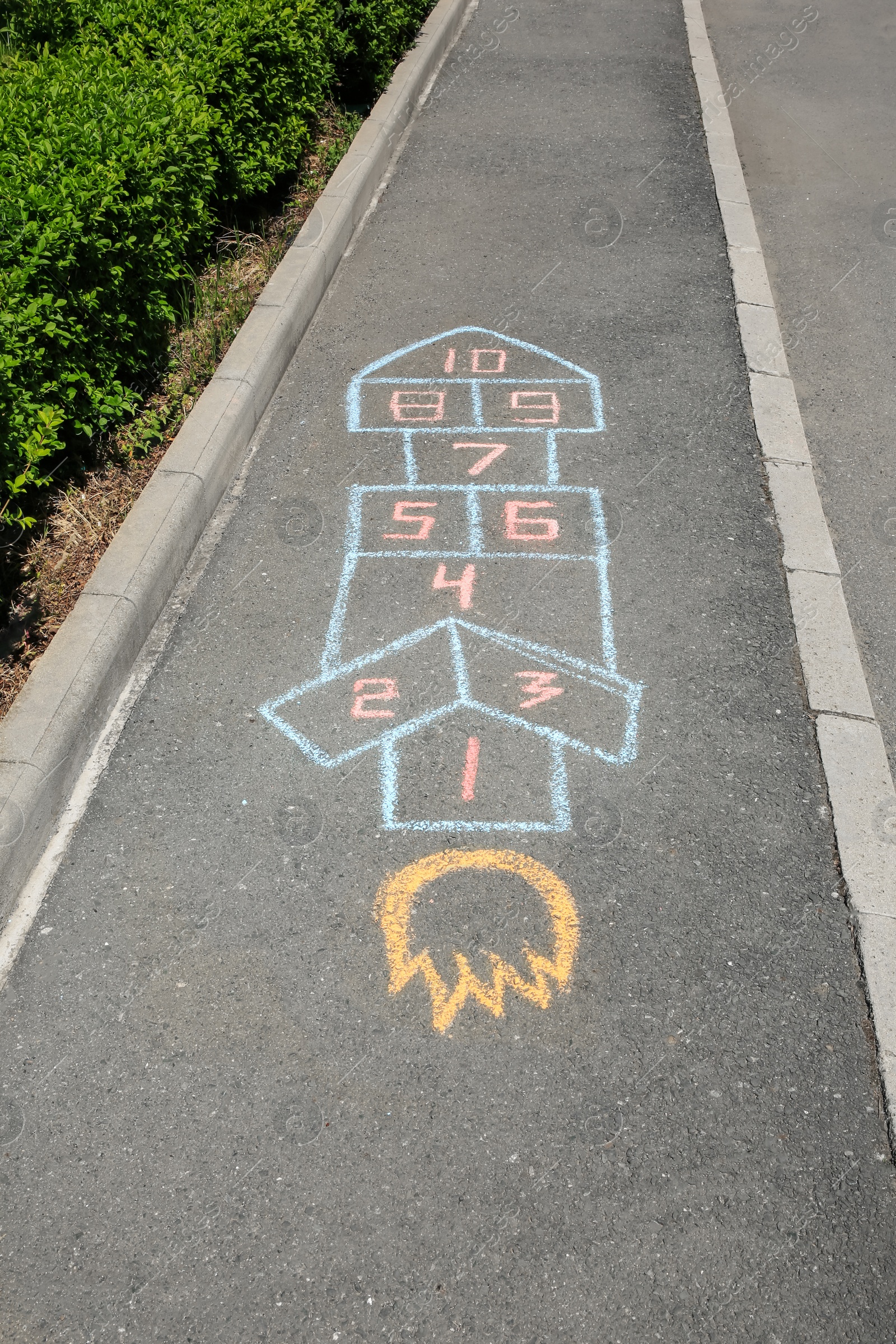 Photo of Hopscotch drawn with colorful chalk on asphalt outdoors