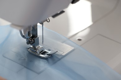 Photo of Sewing machine with light blue fabric, closeup. Space for text