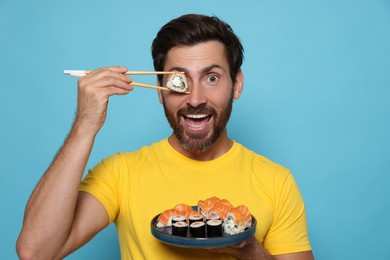 Emotional man hiding his eye with tasty sushi roll on light blue background