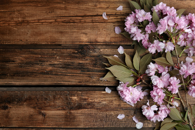 Photo of Sakura tree branch with beautiful blossom on wooden background, space for text. Japanese cherry