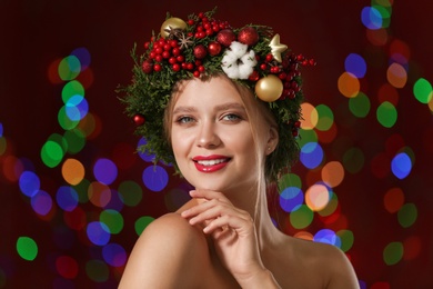 Photo of Beautiful young woman wearing Christmas wreath on blurred background. Bokeh effect