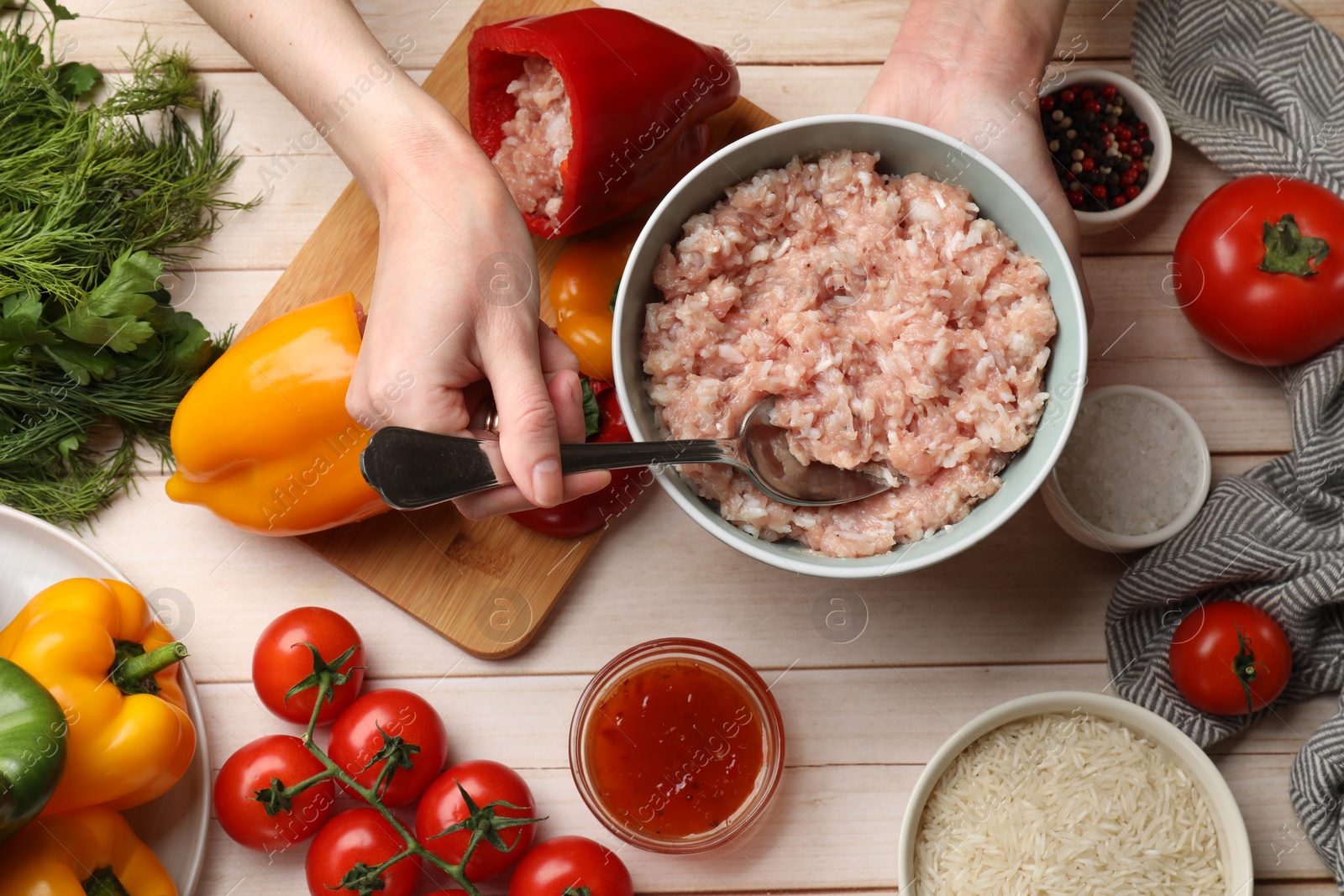 Photo of Woman making stuffed peppers with ground meat at white wooden table, top view