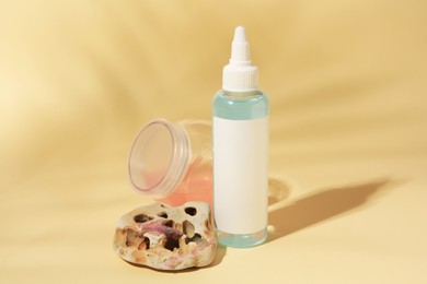 Cosmetic products and stone on beige background