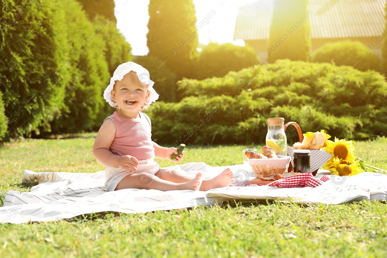 Photo of Cute child sitting on picnic blanket in garden