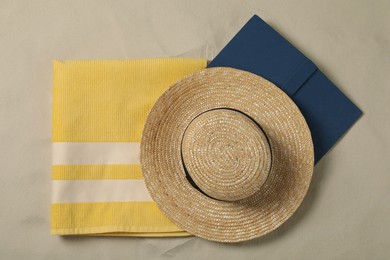 Beach towel, hat and book on sand, top view