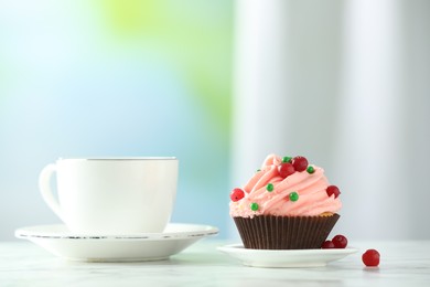 Delicious cupcake with pink cream and tea on white table