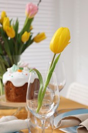 Photo of Beautiful tulip flower in glass indoors. Easter table setting