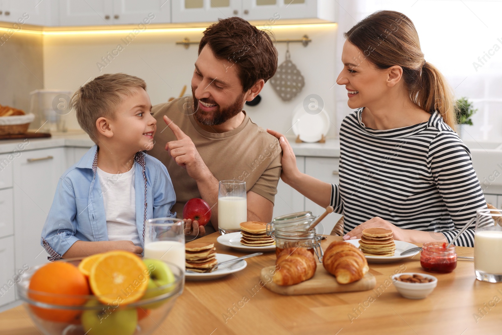 Photo of Happy family having fun during breakfast at table in kitchen