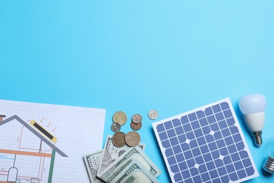 Photo of Flat lay composition with solar panel and money on light blue background. Space for text