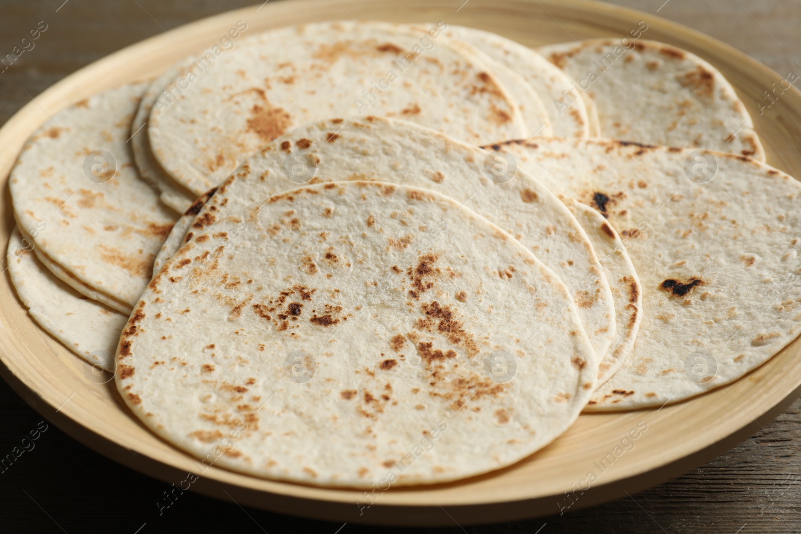 Photo of Many tasty homemade tortillas on wooden table, closeup