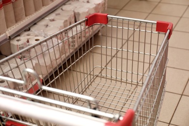 Photo of Empty metal shopping cart in supermarket, closeup