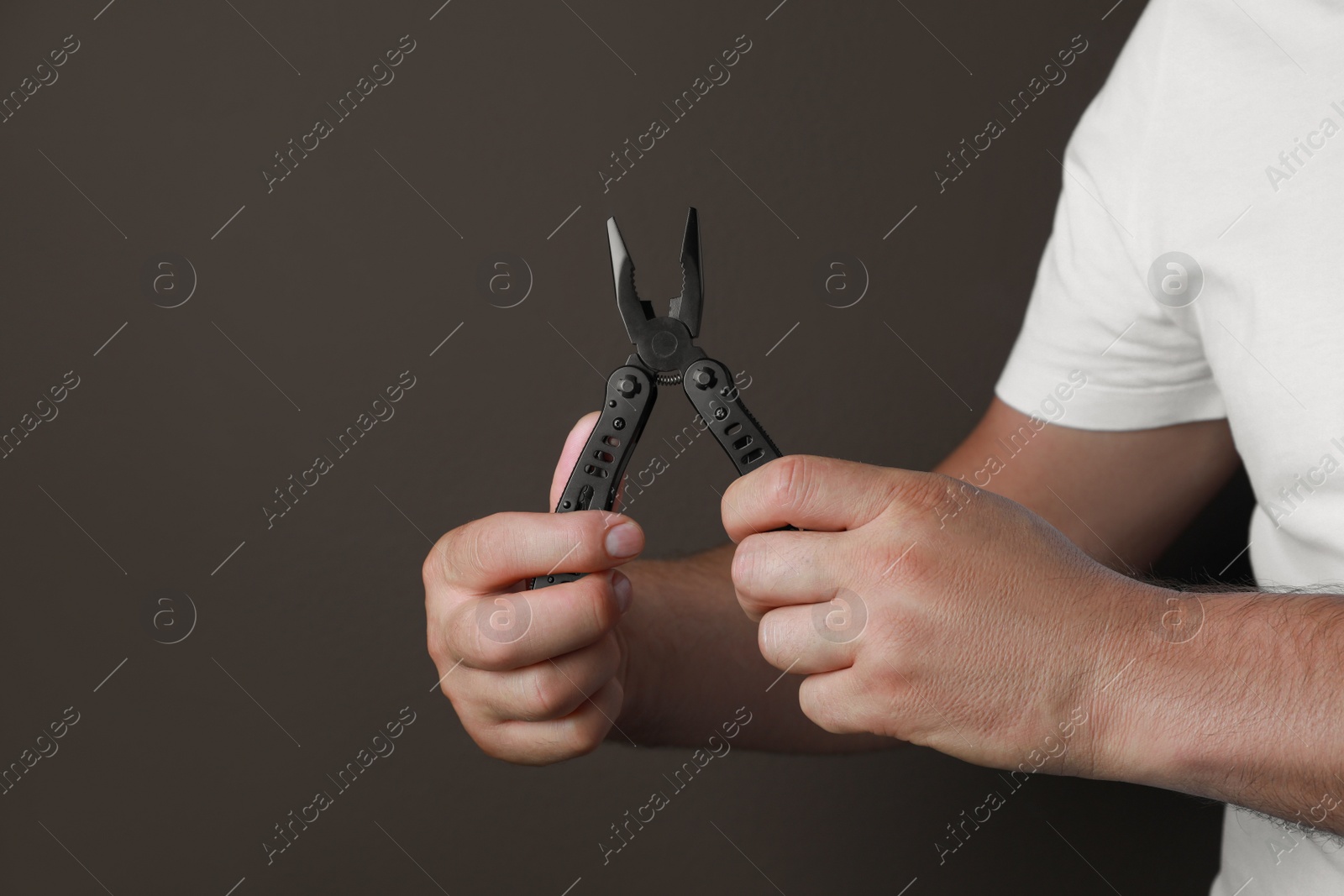 Photo of Man holding multitool on brown background, closeup