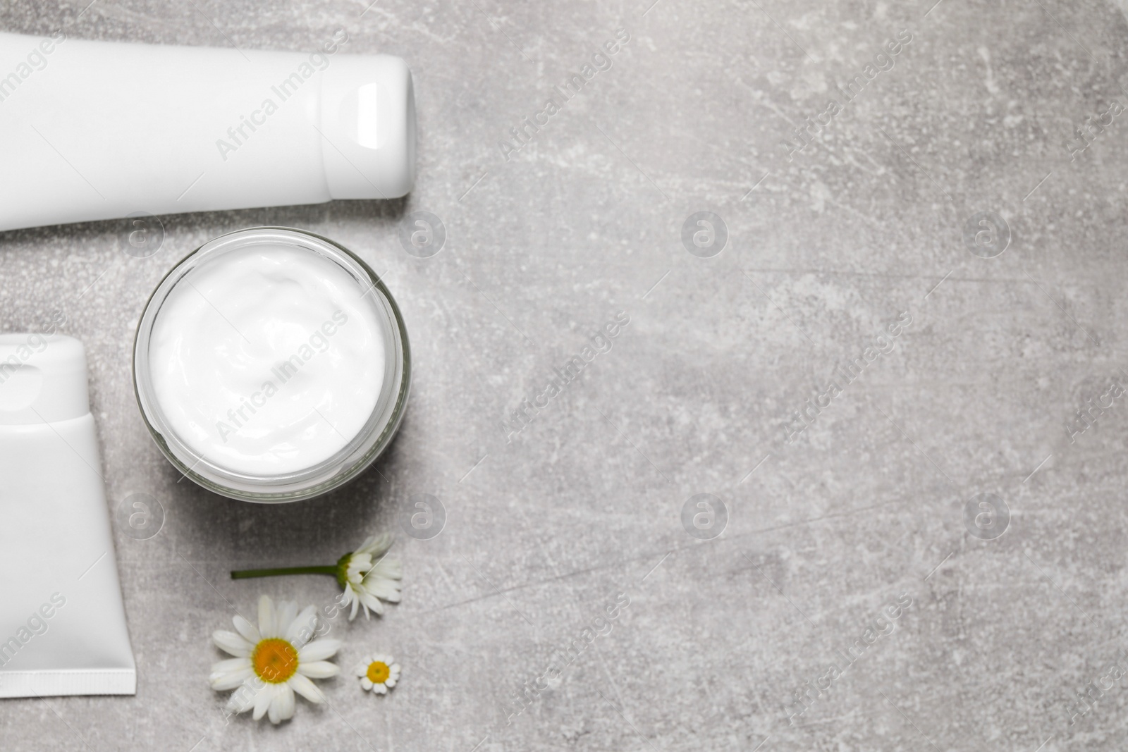 Photo of Different hand care cosmetic products and chamomiles on light grey table, flat lay. Space for text