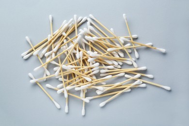 Heap of wooden cotton buds on light grey background, flat lay