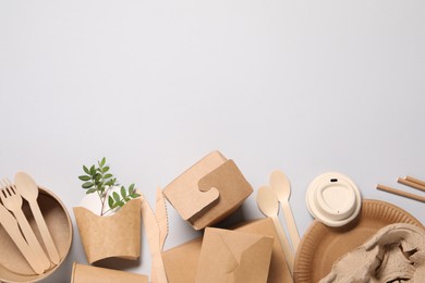 Photo of Eco friendly food packaging. Paper containers, tableware and green twigs on light grey background, flat lay. Space for text