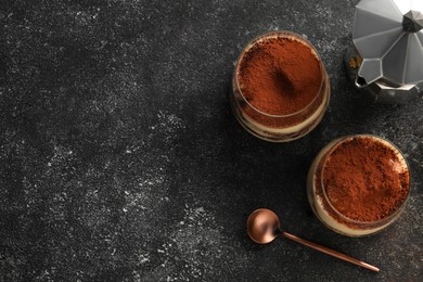 Photo of Delicious tiramisu in glasses served on grey textured table, flat lay. Space for text