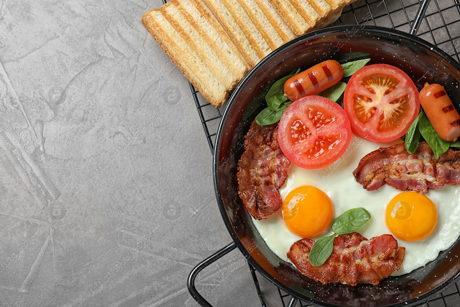 Photo of Delicious breakfast with fried eggs served on grey table, top view. Space for text