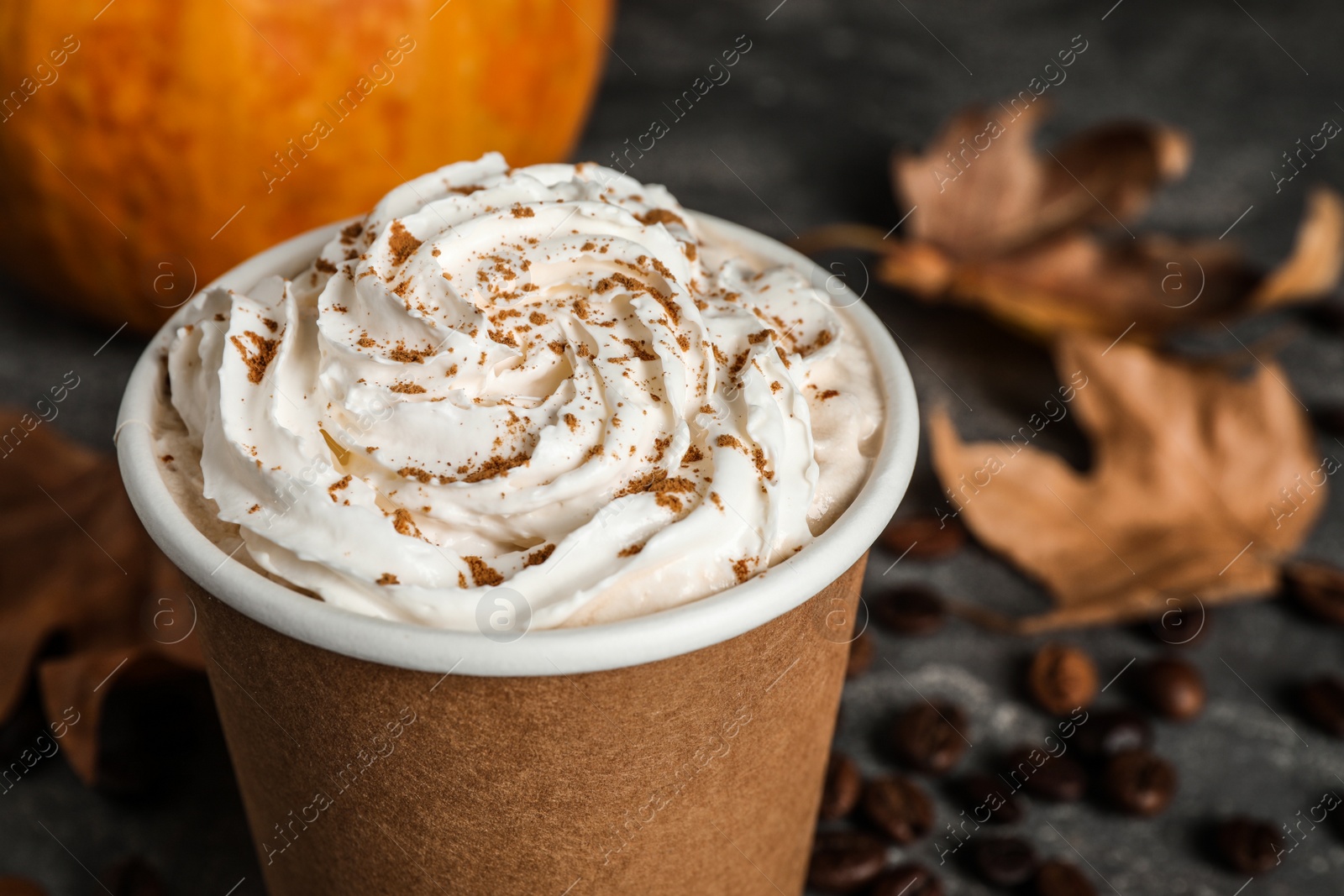 Photo of Paper cup with tasty pumpkin spice latte on grey table, closeup