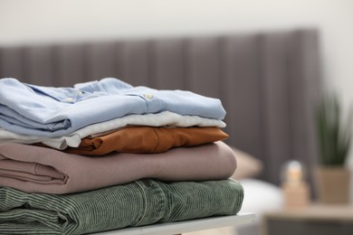 Stack of different folded clothes on table indoors, closeup. Space for text