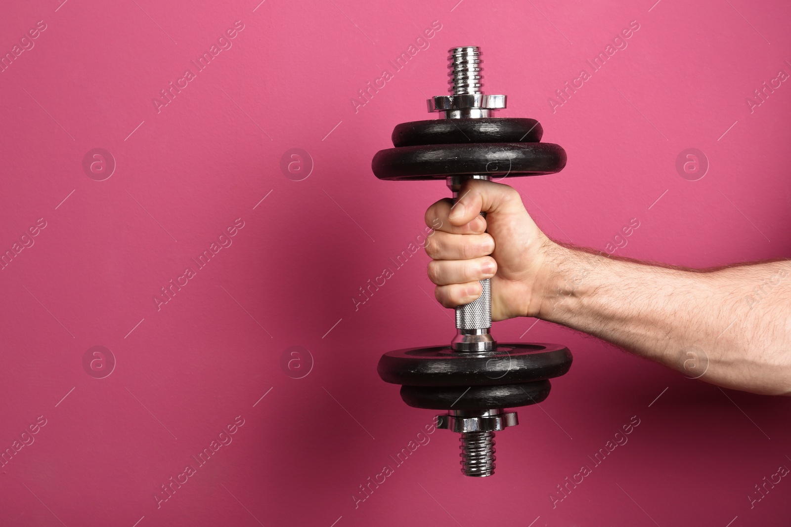 Photo of Male athlete holding metal dumbbell on color background. Space for text