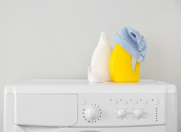 Photo of Bottles of detergent and children's hat on washing machine. Space for text