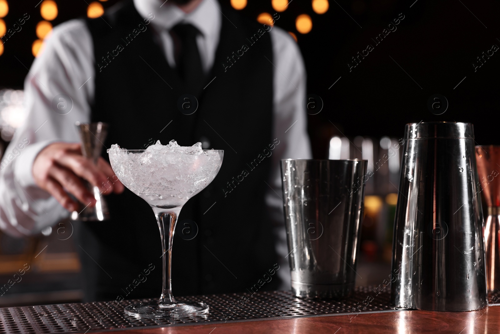 Photo of Bartender preparing fresh alcoholic cocktail in martini glass at bar counter, closeup