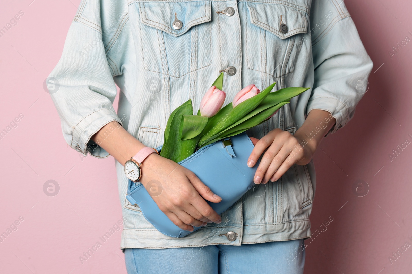 Photo of Stylish woman with bag and spring flowers against color background, closeup