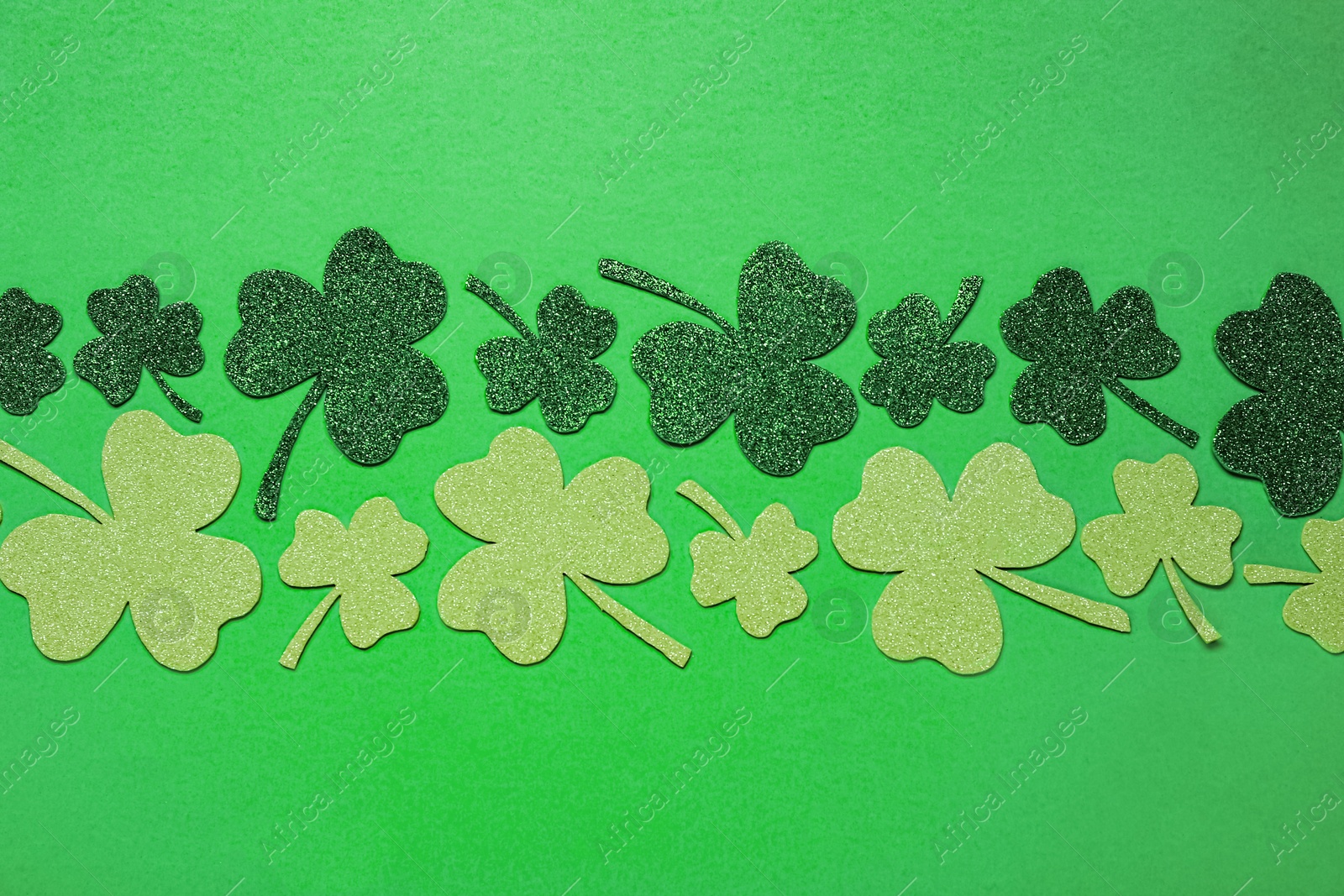 Photo of Flat lay composition with clover leaves on light green background. St. Patrick's Day celebration