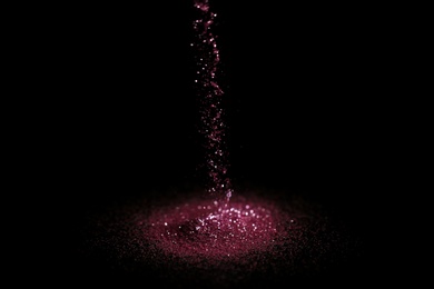 Photo of Sprinkling rose glitter on black background, bokeh effect