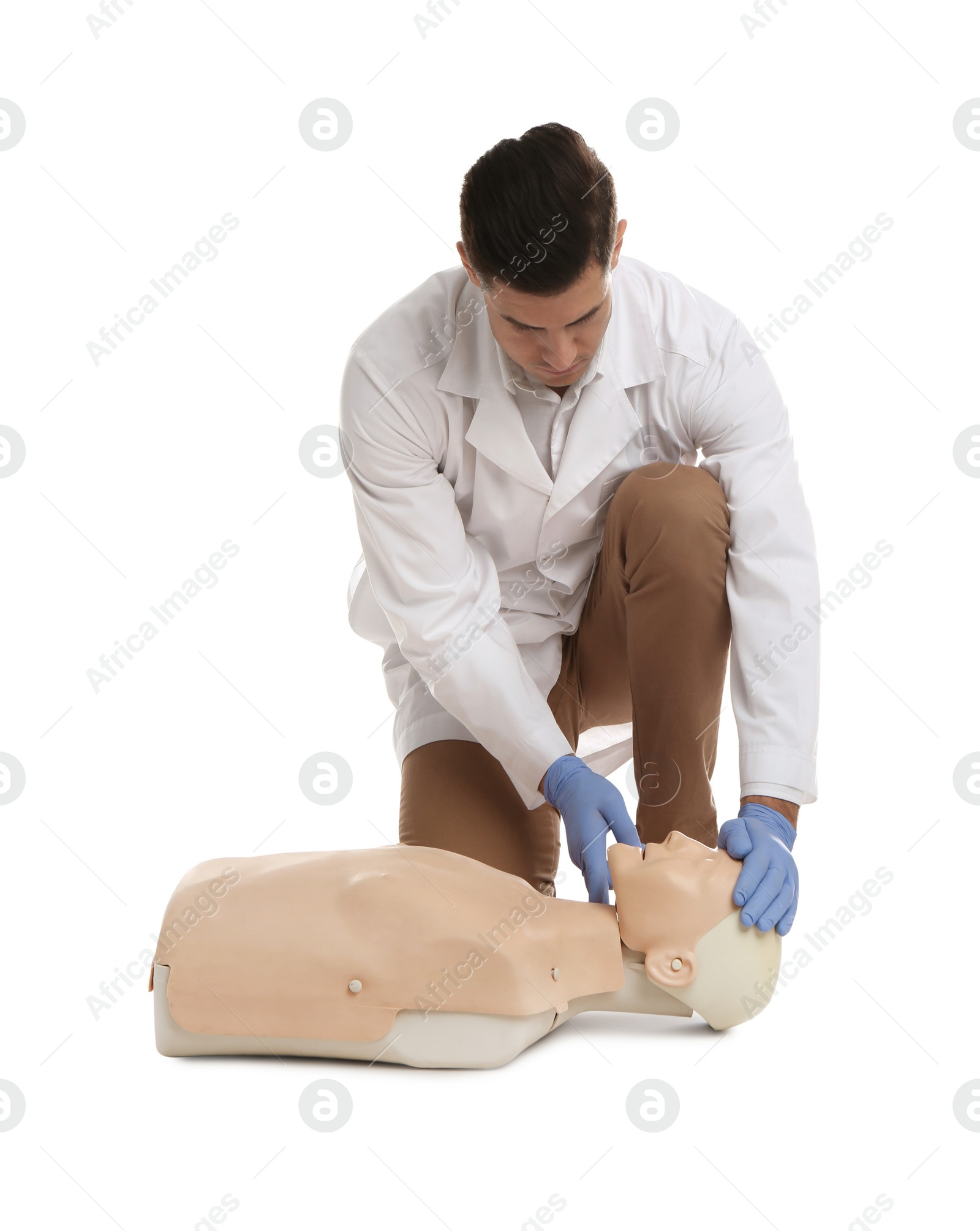 Photo of Doctor in uniform practicing first aid on mannequin against white background