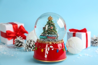 Photo of Beautiful Christmas snow globe and festive decor on light blue background