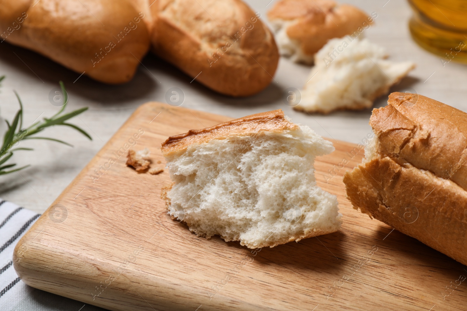 Photo of Broken tasty baguette on white wooden table, closeup