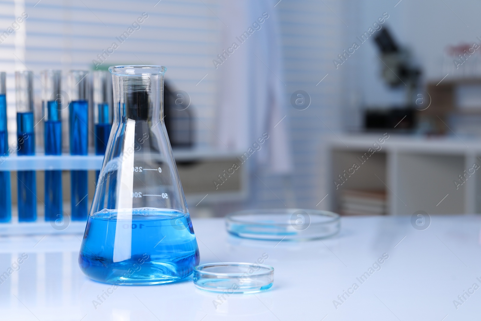 Photo of Laboratory analysis. Different glassware with blue liquid on white table indoors, space for text